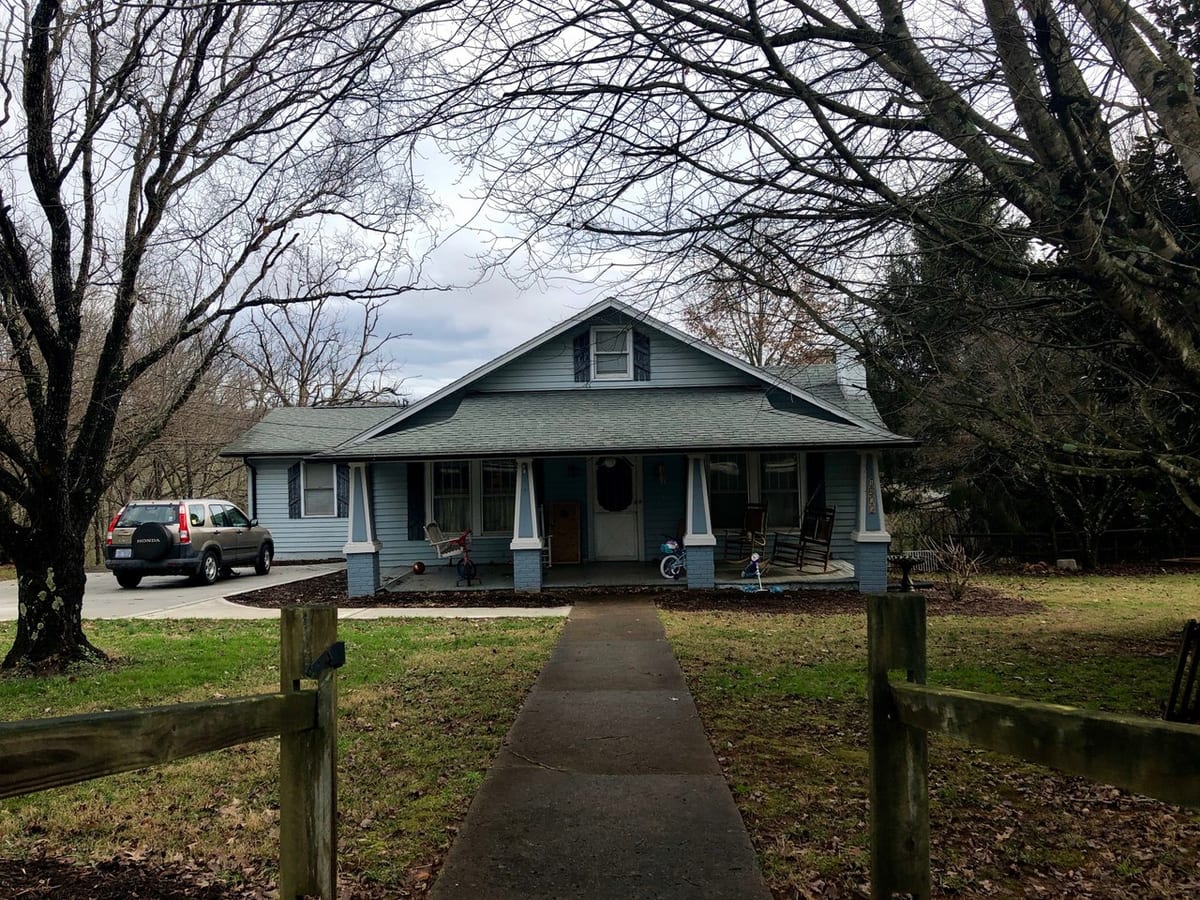 Blue Craftsman house with covered porch, front path and fence posts before AI exterior redesign