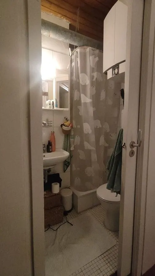 A very small bathroom with a shower curtain, a small sink and white mosaic floor tiles