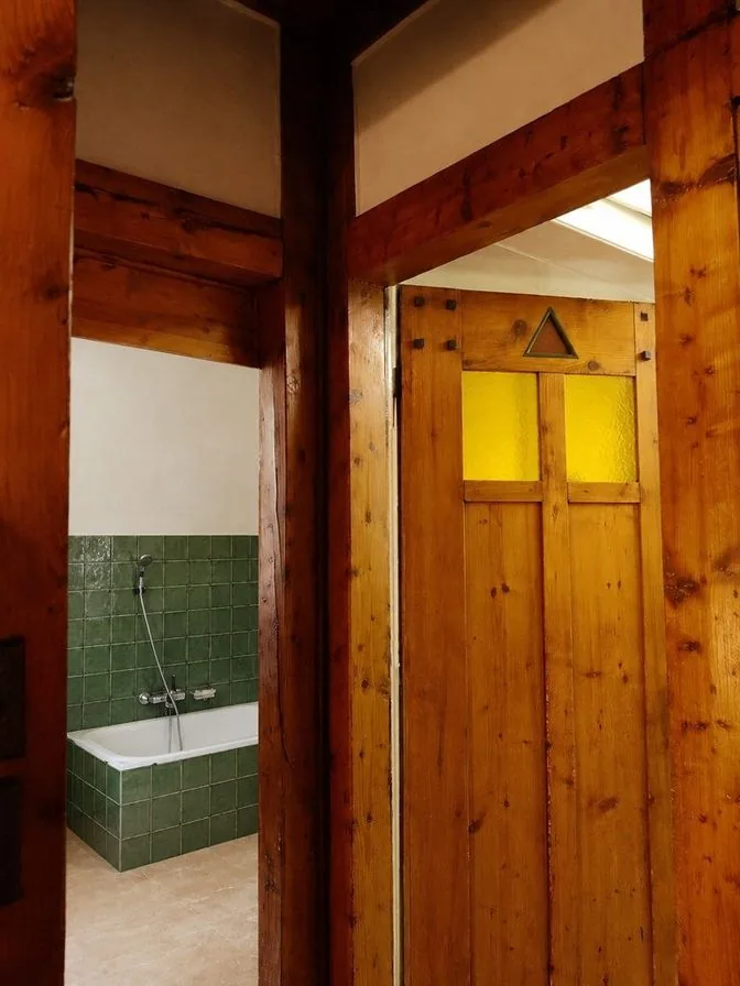 The same bathroom as a retiling AI concept with green glazed wall tiles and a pale stone-look floor