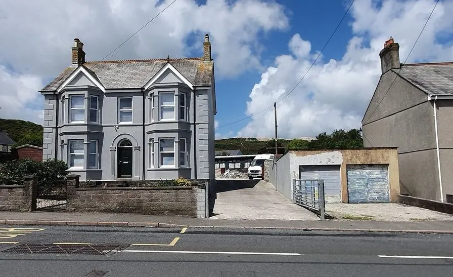 A gray stucco house with bay windows and white trim on a village street