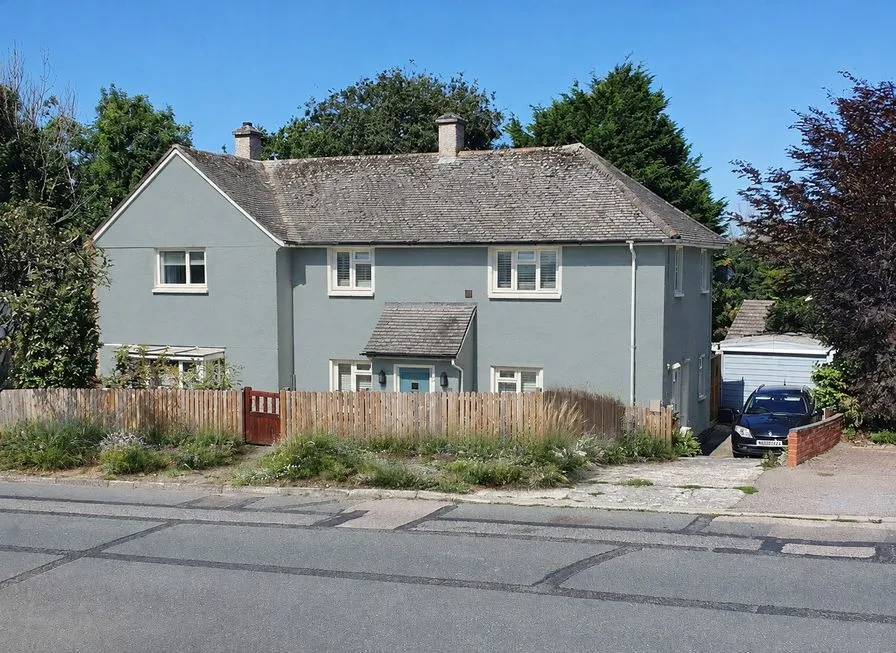 The same houses as an AI concept with pale gray-blue stucco, white trim and grasses along the fence