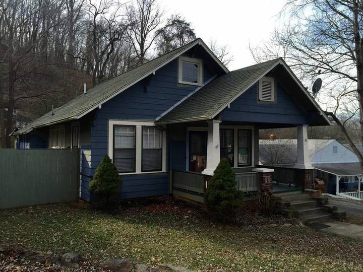 A craftsman bungalow repainted in navy with white trim, with spec tags on the siding and trim